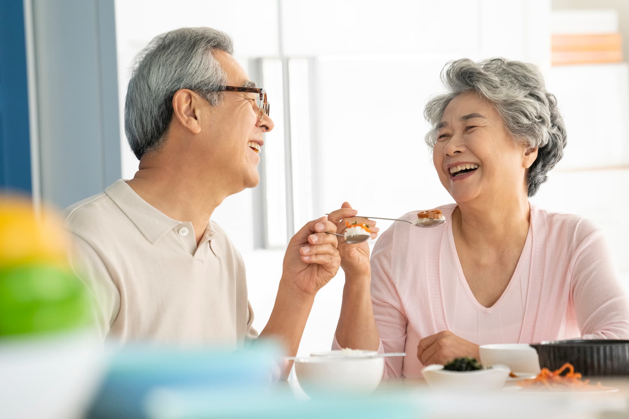 入れ歯を使用して仲良く食事をする高齢夫婦