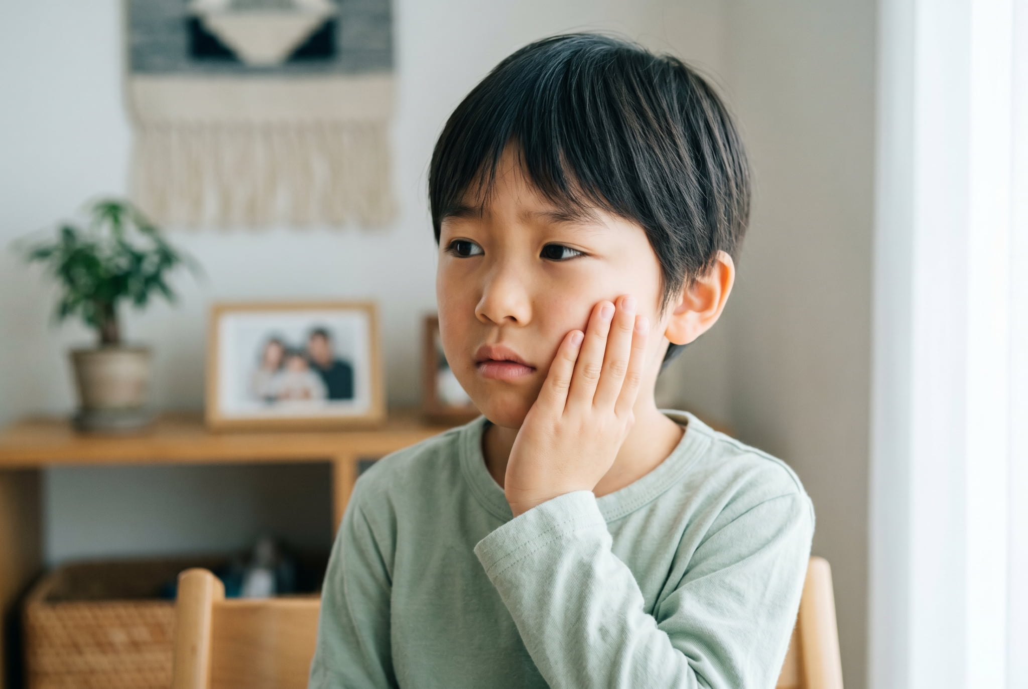 虫歯になって歯を抑える男の子