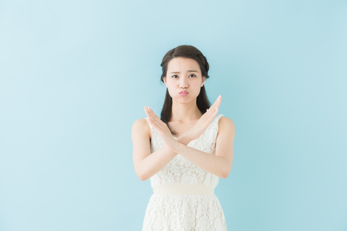 両手でバツマークをする女性