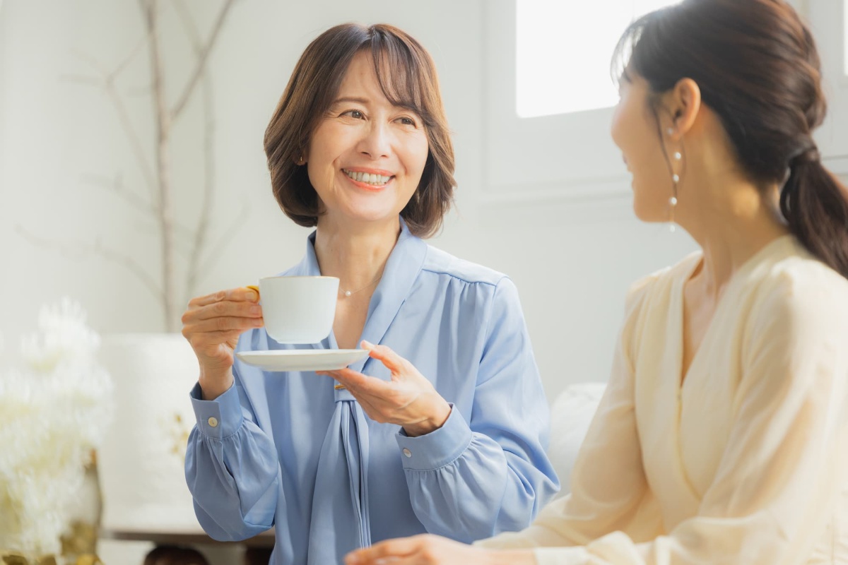 コーヒーを飲みながら友人と会話を楽しむ女性