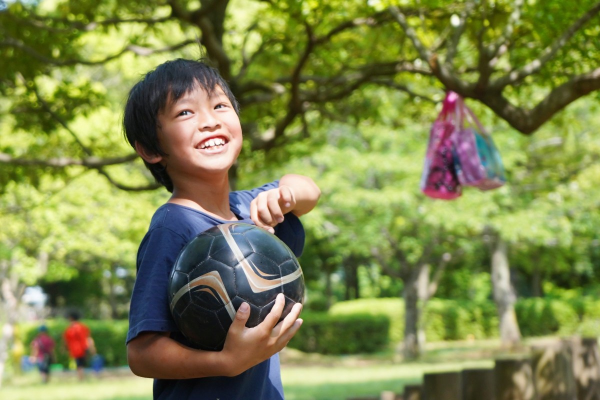 サッカーボールを手に持った笑顔の子ども